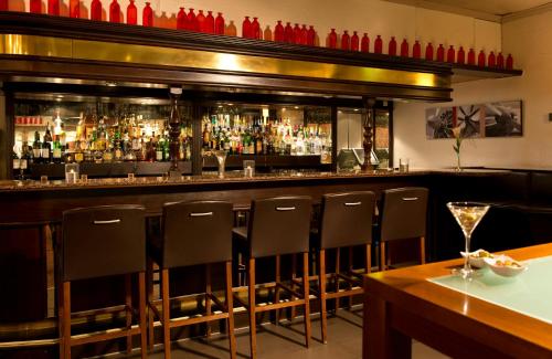 a bar with a row of chairs in a restaurant at Leonardo Hotel Köln Bonn Airport in Cologne
