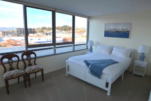 a bedroom with a bed and two chairs and a window at Prime Luxury Penthouse Living in Launceston