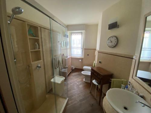 ein Badezimmer mit Dusche, Toilette und einer Wanduhr. in der Unterkunft Rainerio 06 in Fano