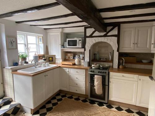 a kitchen with white cabinets and a stove top oven at Bewdley Riverside Cottage in Bewdley