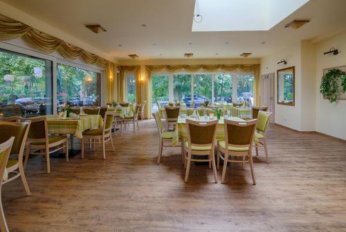 a dining room with tables and chairs and windows at Hotel Seeschlösschen in Groß Köris