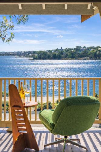 a green chair sitting on a deck with a view of the water at Ocean-View Art Stay & Private Rooftop, Walk to Circular Quay in Sydney