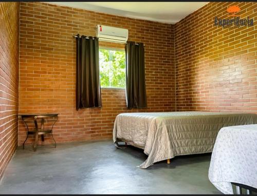 a bedroom with a bed and a brick wall at Chácara Galileia in Trindade