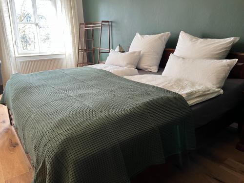 a bed with a green and white blanket and a window at Schloss1611 B&B in Erbendorf