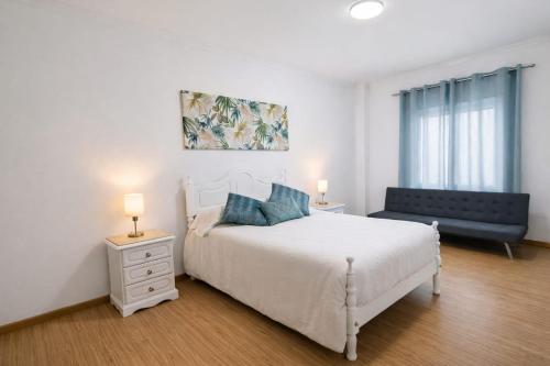 a white bedroom with a bed and a chair at Casa do Paraíso in Elvas