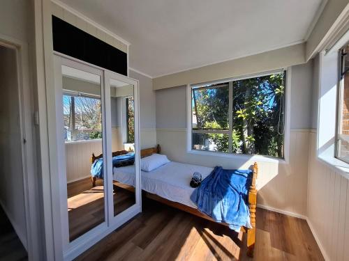 a small bedroom with a bed and two windows at All decked out in Rotorua