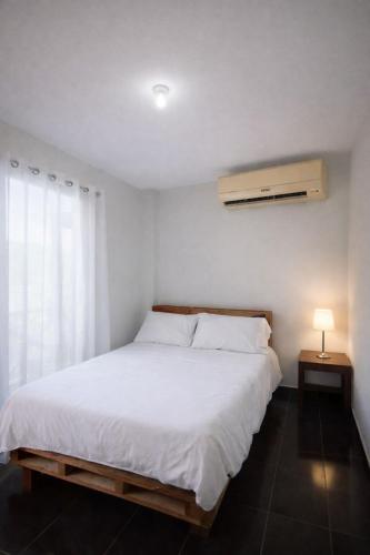 a bedroom with a white bed and a window at Villa azul círculo auto in Jarabacoa