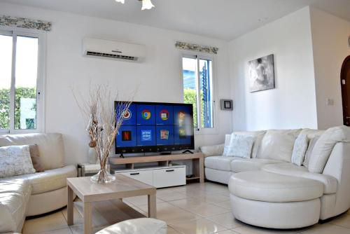 a living room with white furniture and a flat screen tv at Latchi Beach Front Villa - Private Heated Pool - Amazing Uninterrupted Sea Views in Polis Chrysochous