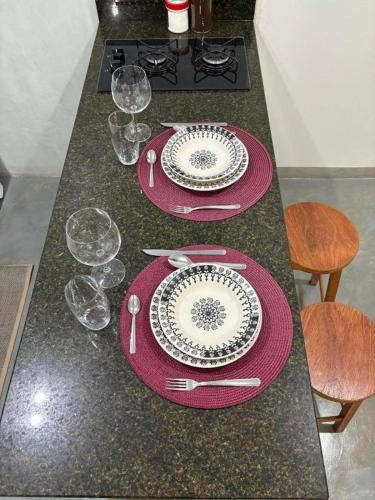 a table with two plates and wine glasses on it at Studio 4 - Solteiro in Aracruz