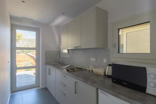 a kitchen with white cabinets and a window at Lavender Cove in Korfos