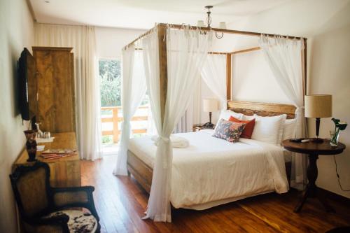 a bedroom with a canopy bed and a window at Pousada Tucano Do Cuiabá in Itaipava