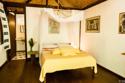 a bedroom with a bed with yellow sheets and a ceiling at Pousada Too Cool in Diogo