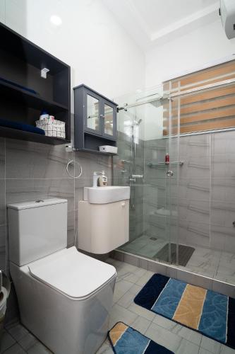 a bathroom with a toilet and a glass shower at Cherry Signature Condos in Adentan