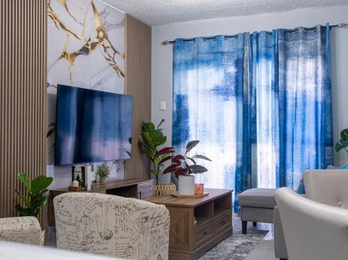 a living room with a television and blue curtains at East Lake Oasis in Arima