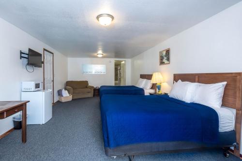 a bedroom with a blue bed and a couch at Cascade Motel in Oakridge