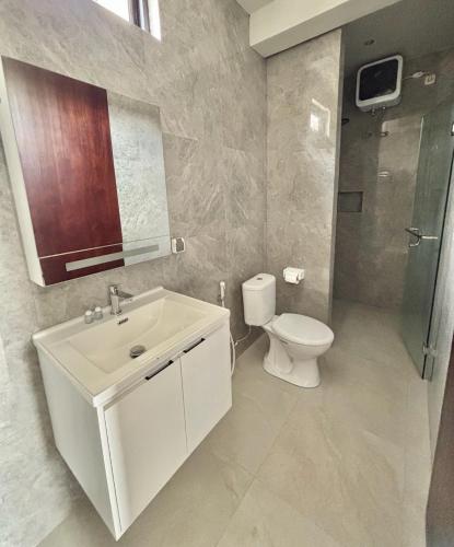 ein Badezimmer mit einem weißen Waschbecken und einer Toilette in der Unterkunft Leafy's Lodge in Padangnegeri