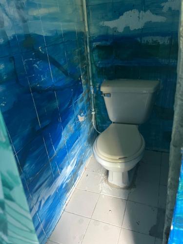 a bathroom with a toilet and blue tiled walls at Hostal el peñón in Buenaventura