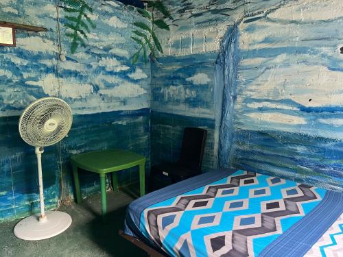 a room with a bed and a fan and a chair at Hostal el peñón in Buenaventura