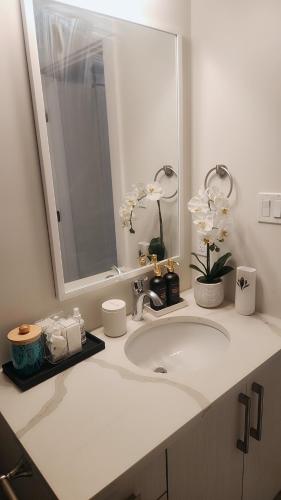 a white bathroom with a sink and a mirror at Hebzibah's Luxe in Prince George