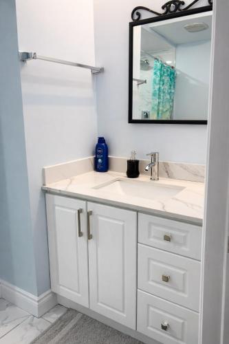 a bathroom with a white sink and a mirror at Modern 2BR Basement Suite Private Entrance in Brampton