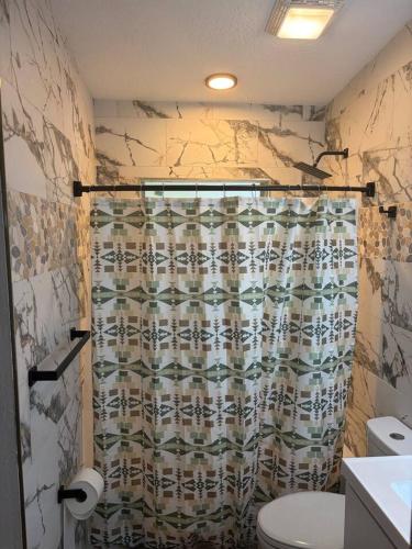 a bathroom with a shower curtain and a toilet at Amelia’s Arena Retreat in Orlando