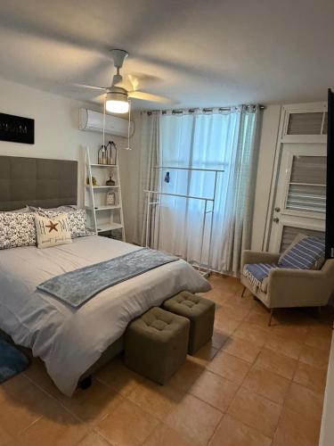 a bedroom with a large bed and a chair at NaboBlue Ocean View Apartment Maunabo PR in Maunabo