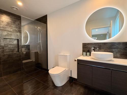 a bathroom with a toilet and a sink and a mirror at Style, Space and Comfort in Twizel