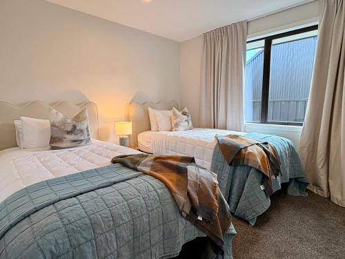 two beds in a bedroom with a window at Style, Space and Comfort in Twizel