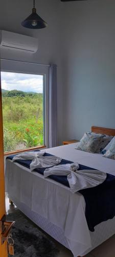 a bedroom with a bed with a large window at Pousada do Nondas in Estivado