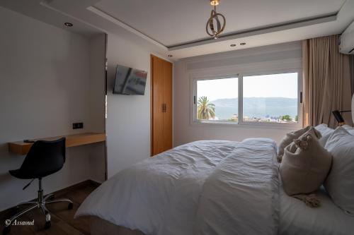 a bedroom with a bed and a desk and a window at RamoHouse bright home central in Chefchaouen