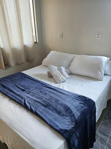 a large white bed with a blue blanket on it at Studio 04 in Aracruz