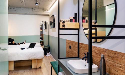 a room with a bed and a sink and a mirror at LyLo Auckland in Auckland