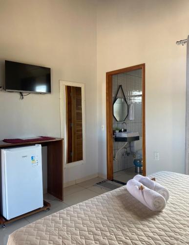 a bedroom with a bed with a tv on the wall at Pousada do Nondas in Estivado