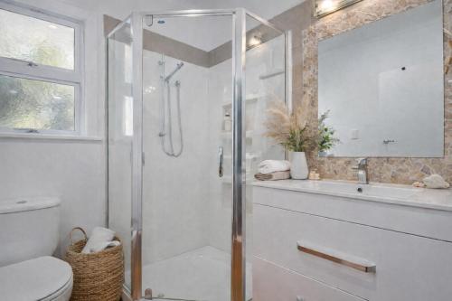 a bathroom with a shower and a toilet and a sink at Lukes Kitchen Bach in Kuaotunu