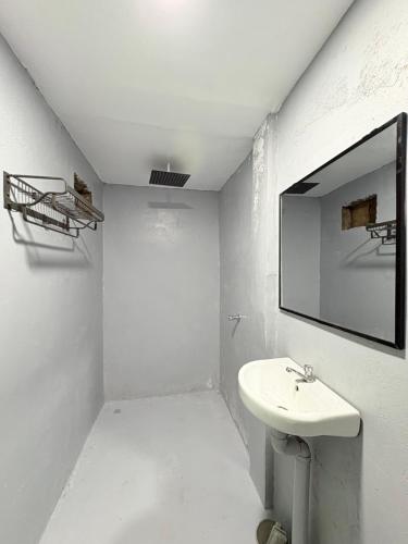 a white bathroom with a sink and a mirror at Jaydy Guest House in General Luna