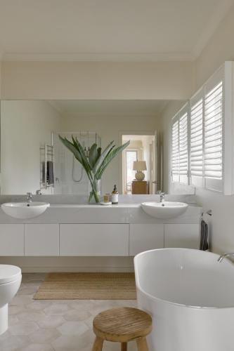 a white bathroom with two sinks and a tub at Verandah Retreat - A Beach House by the sea in Cowes
