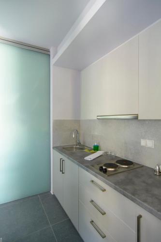 a kitchen with white cabinets and a sink at Lavender Cove in Korfos