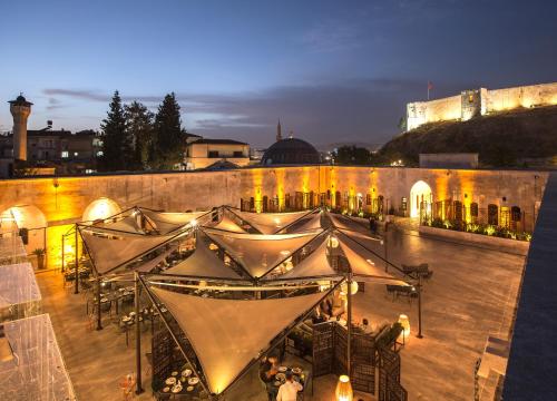 a group of people sitting at tables in front of a building at HSVHN Hotel Hışvahan in Gaziantep