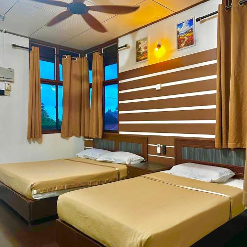 a bedroom with two beds and a ceiling fan at Johans Chalet & Restaurant in Tioman Island