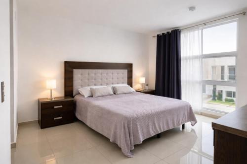 a bedroom with a bed and a large window at Acogedora y amplia casa, alberca climatizada previa reserva in Juriquilla