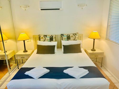 a bedroom with a large white bed with two lamps at Palm Cove Tropic Apartments in Palm Cove