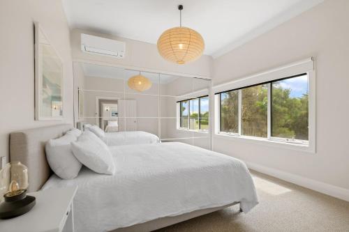 a white bedroom with two beds and a window at Surf Beach Remote Retreat in Surf Beach
