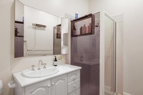 a white bathroom with a sink and a shower at Surf Beach Remote Retreat in Surf Beach