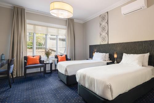 a hotel room with two beds and a chair at Sovereign Hill Hotel in Ballarat