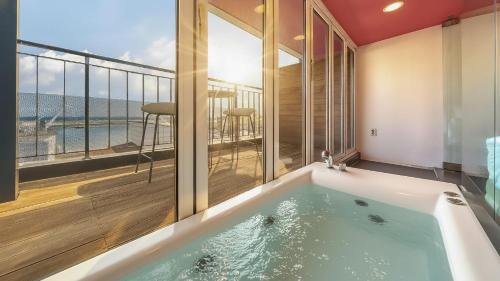 a bath tub in a room with a balcony at Sokcho Maru Pension in Sokcho