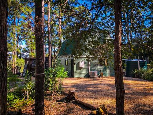 a green cabin in the middle of trees at LAKE VIEW CHALET Australia Zoo close by in Landsborough