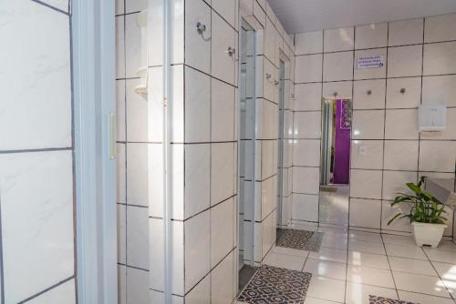 a bathroom with a shower with white tiled walls at Pousada ExpoBH in Belo Horizonte