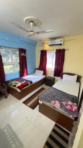 two beds in a room with red curtains at Rama Guest House in Bodh Gaya