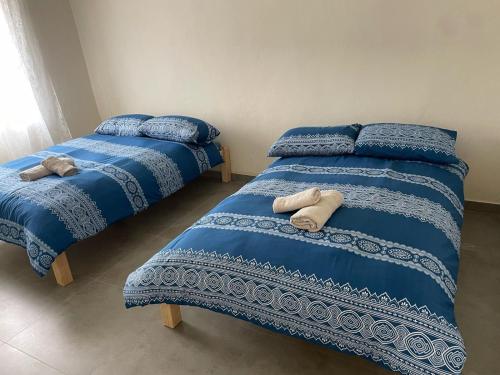 two beds in a bedroom with blue blankets and pillows at beit al moukhtar in Ḩārat at Taḩtā
