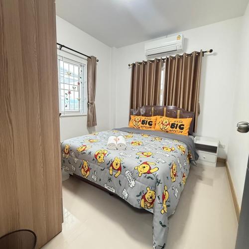 a bedroom with a bed with a comforter on it at Kitjamyhome2 in Ban Tha Thon